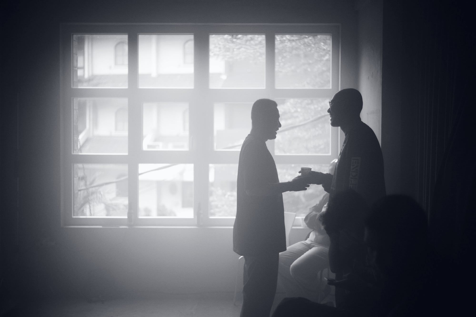 Two people in conversation, silhouetted against a bright window.