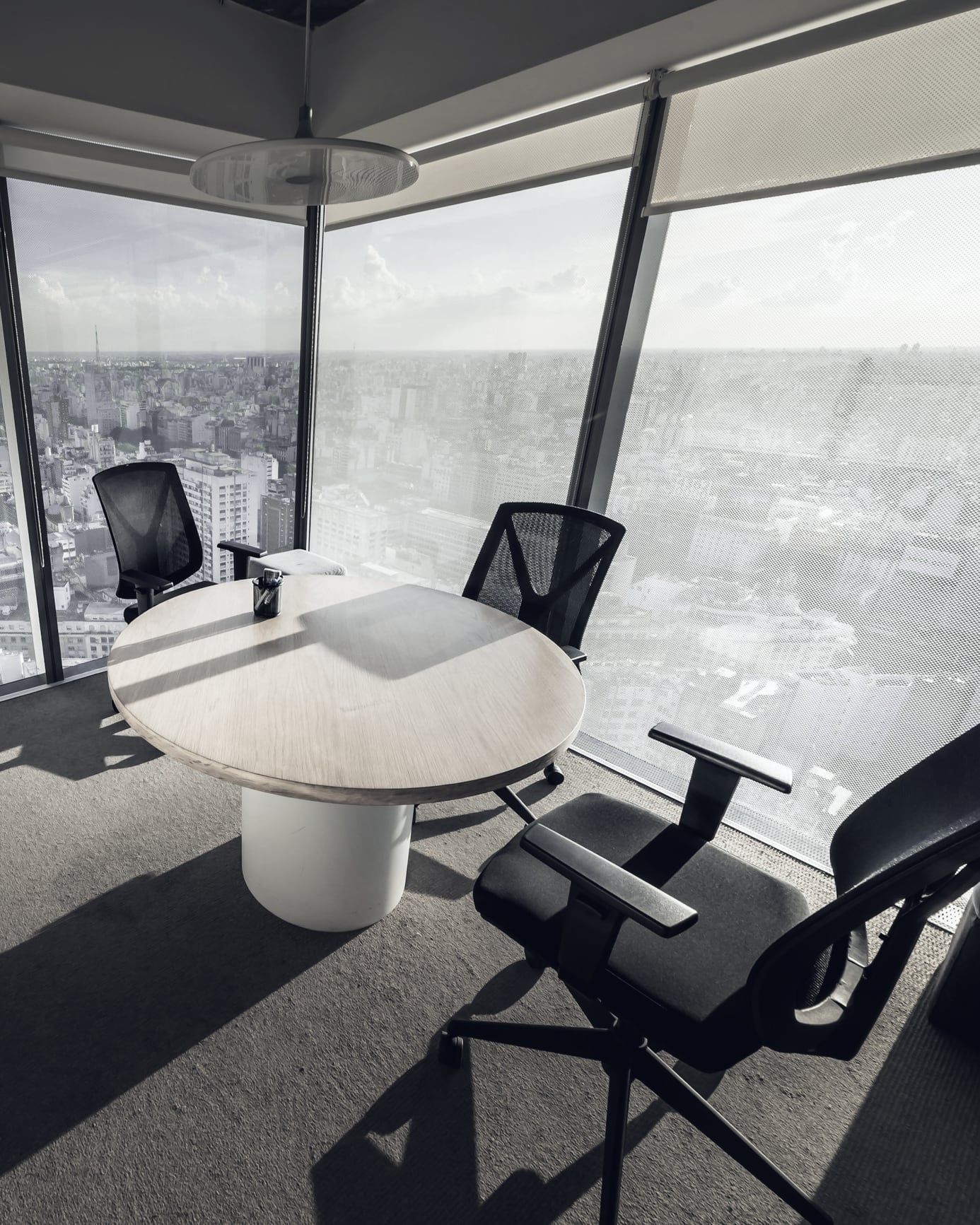 Afternoon light and long shadows in a corner meeting room high above a city.